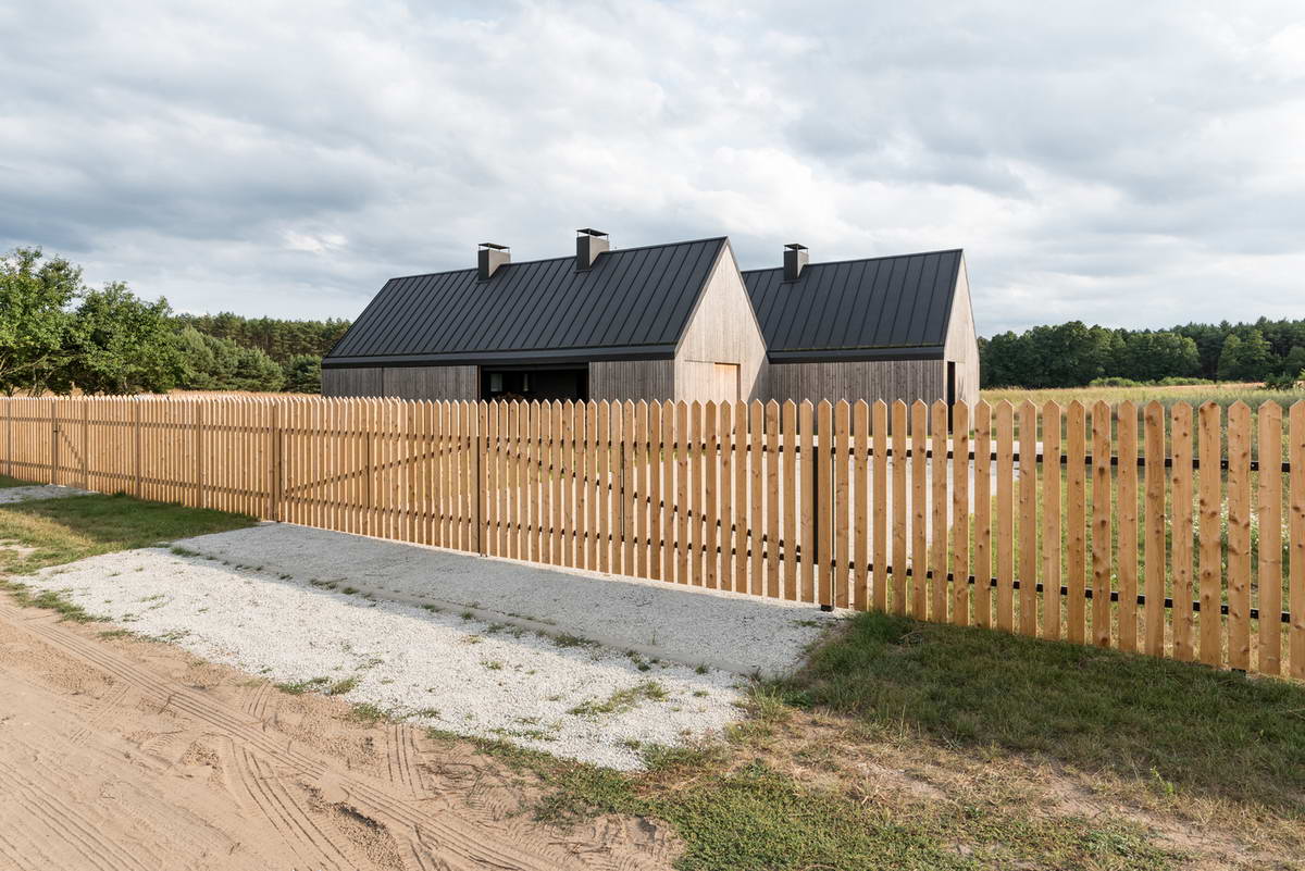 Деревянный дом на лугу с традиционным забором в Польше